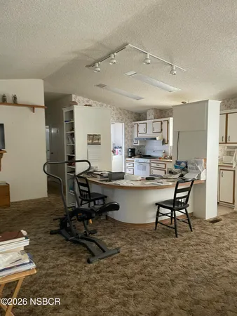 a room with dining table chairs wooden floor and view kitchen