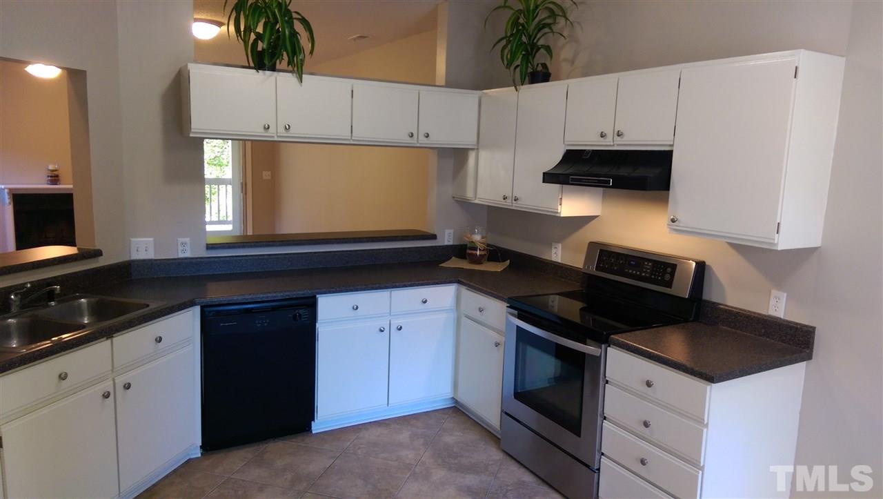 6151 Summer Pointe Place, Unit 202 Raleigh, NC 27606 - Photo 2 of 21 a kitchen with granite countertop white cabinets and black appliances