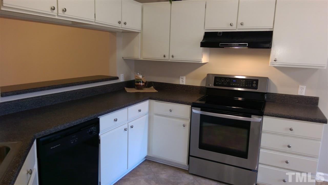 6151 Summer Pointe Place, Unit 202 Raleigh, NC 27606 - Photo 5 of 21 a kitchen with granite countertop white cabinets and black appliances