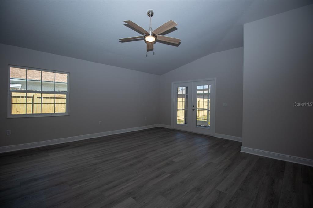 5422 Charles Street New Port Richey, FL 34652 - Photo 13 of 30 an empty room with wooden floor fan and windows