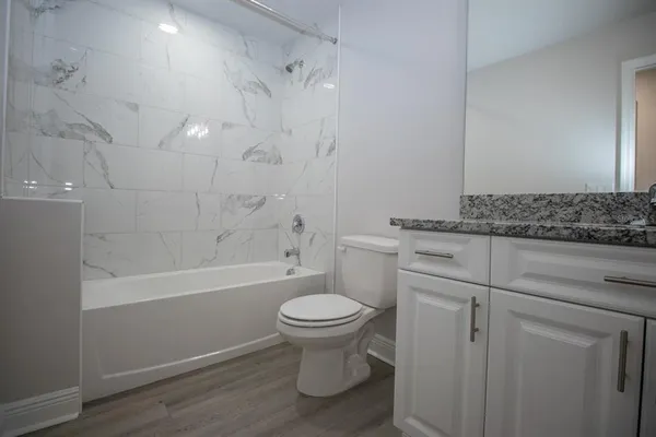a bathroom with a granite countertop toilet a sink and a bathtub