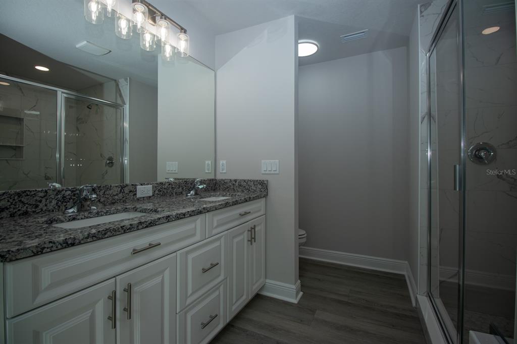 5422 Charles Street New Port Richey, FL 34652 - Photo 24 of 30 a bathroom with a granite countertop sink a large mirror and a vanity