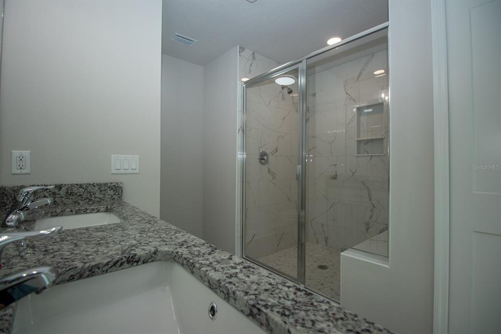 5422 Charles Street New Port Richey, FL 34652 - Photo 25 of 30 a bathroom with a granite countertop sink a mirror and shower