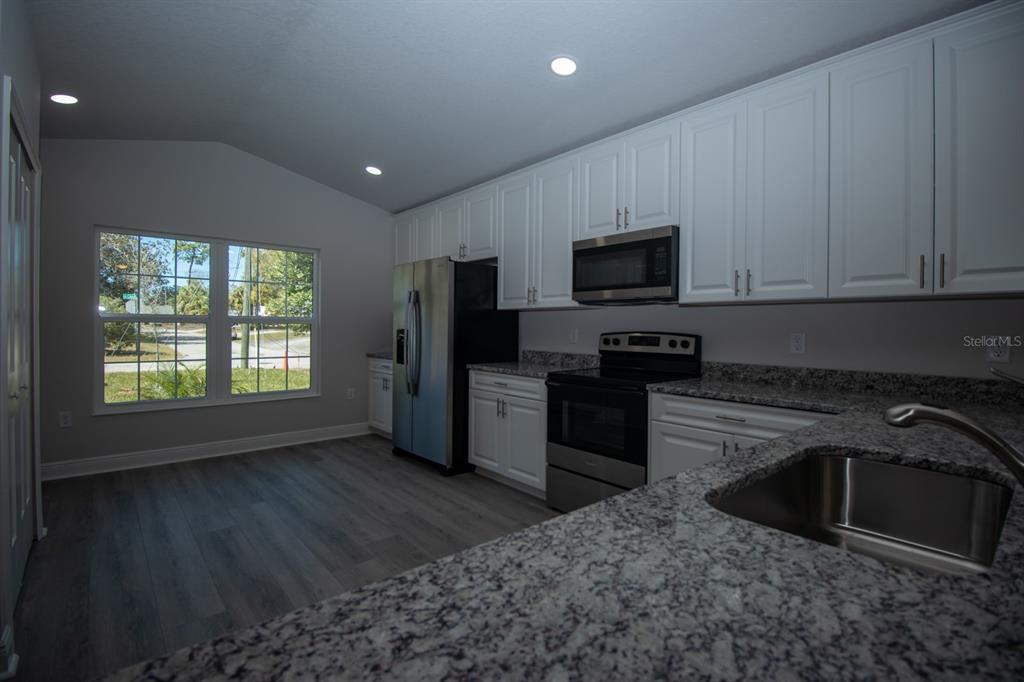 5422 Charles Street New Port Richey, FL 34652 - Photo 10 of 30 a kitchen with granite countertop a refrigerator stove and microwave