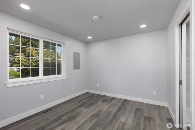 an empty room with wooden floor and windows