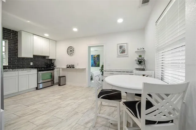 a kitchen with a sink a stove cabinets and a dining table