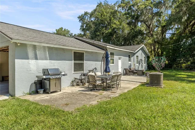 a view of a patio with table and chairs potted plants and large tree