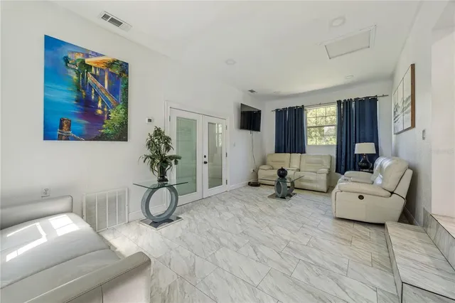 a living room with furniture and a gym machine with wooden floor
