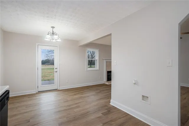 an empty room with wooden floor chandelier and windows