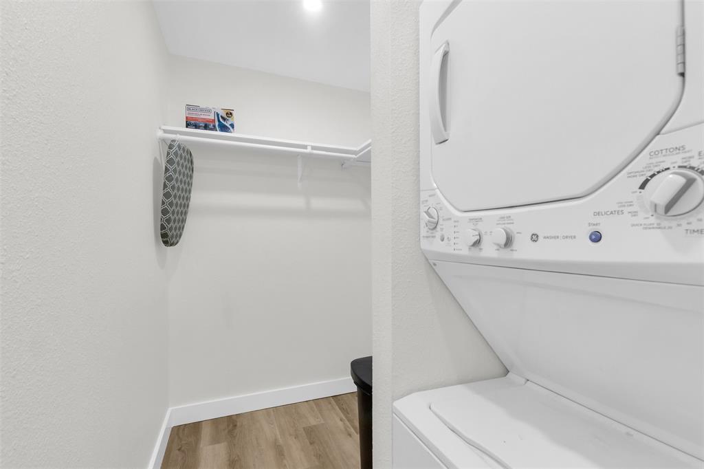 4121 Junius Street, Unit B Dallas, TX 75246 - Photo 18 of 32 Dedicated laundry area featuring a stackable washer and dryer unit, wood-finish flooring, and a built-in shelving system