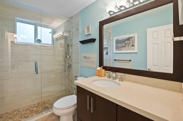 a bathroom with a granite countertop sink toilet and shower