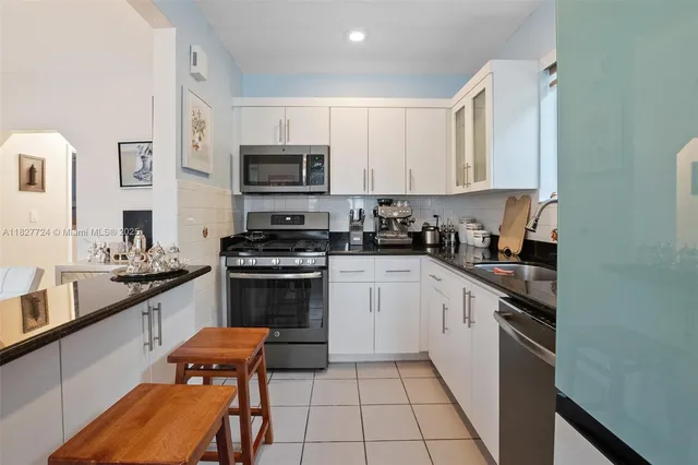 a kitchen with stainless steel appliances granite countertop a stove top oven a sink dishwasher and a refrigerator with wooden cabinets