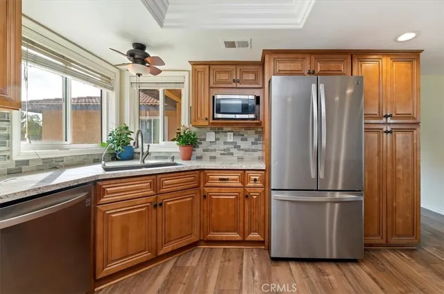 a kitchen with granite countertop stainless steel appliances a refrigerator cabinets and wooden floor
