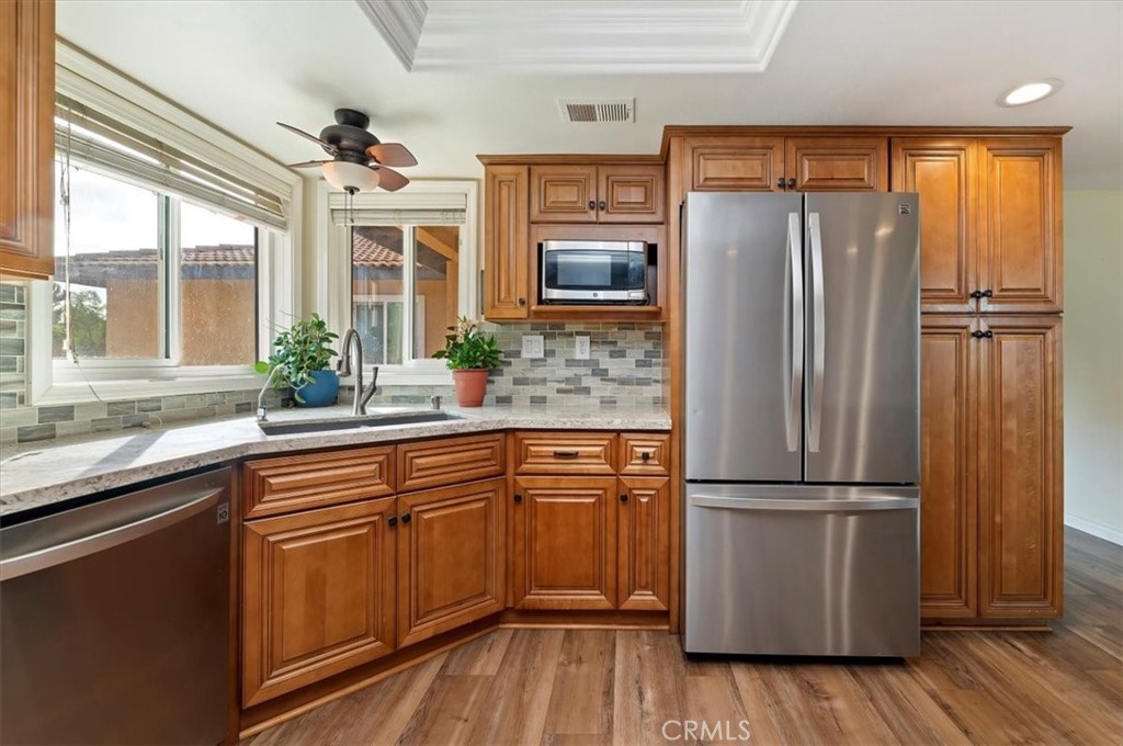 14231 Alexander Street Riverside, CA 92508 - Photo 15 of 36 a kitchen with granite countertop stainless steel appliances a refrigerator cabinets and wooden floor