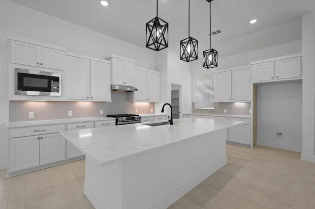 a large kitchen with stainless steel appliances a large counter top a stove and a refrigerator