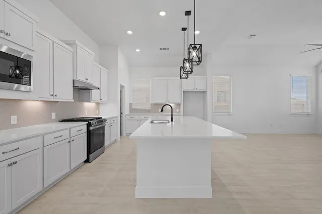 a kitchen with stainless steel appliances granite countertop a sink a stove and cabinets