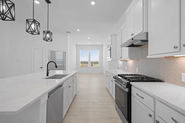 a large white kitchen with kitchen island a stove a sink dishwasher and a refrigerator with wooden floor