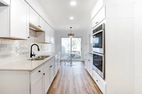 a kitchen with kitchen island a sink appliances cabinets and a large window