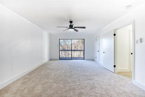 an empty room with windows and a ceiling fan
