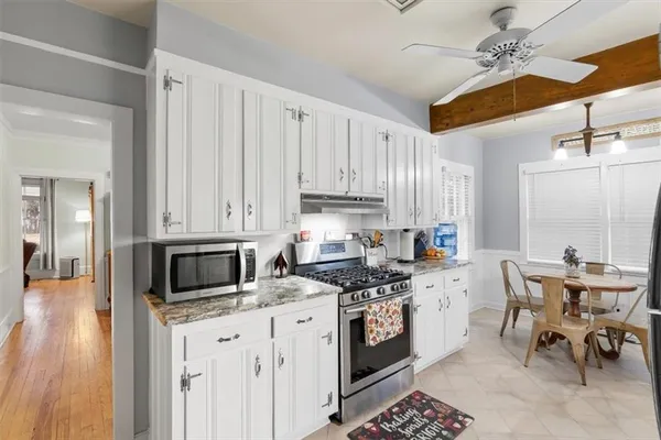 a kitchen with stainless steel appliances granite countertop a stove a sink dishwasher and white cabinets with wooden floor