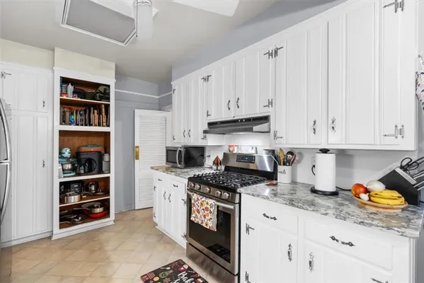 a kitchen with stainless steel appliances granite countertop a stove and a white cabinets