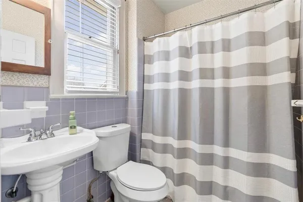 a bathroom with a sink a toilet a mirror and shower curtain