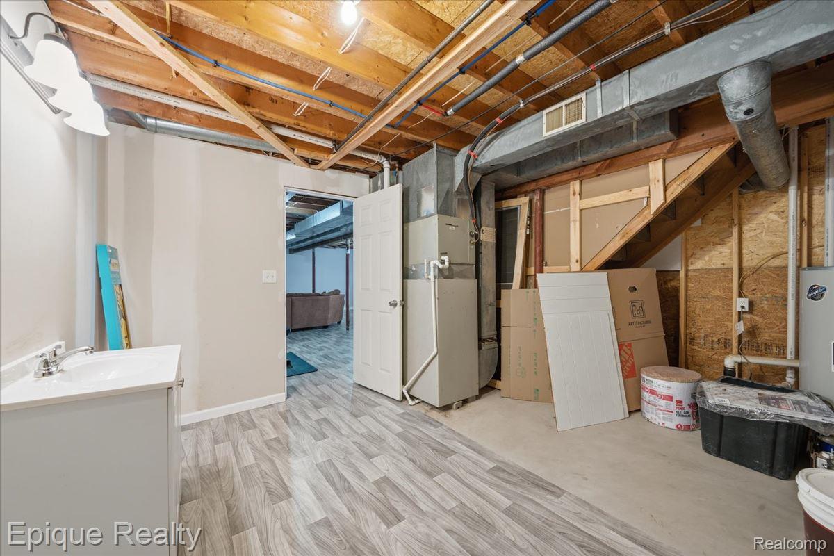 12272 East Mt Morris Road Davison, MI 48423 - Photo 23 of 39 Unfinished basement space featuring exposed ceiling joists, light wood-finish flooring, and a white vanity with an integrated sink