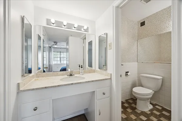 a bathroom with a granite countertop sink a toilet a mirror and shower