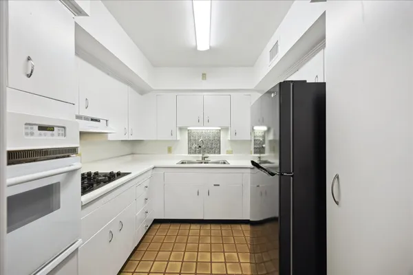 a kitchen with a sink a refrigerator and cabinets