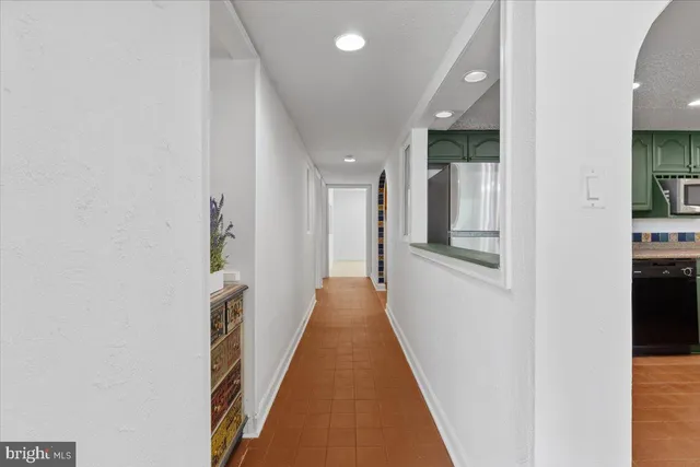 a view of a hallway with wooden floor and a living room