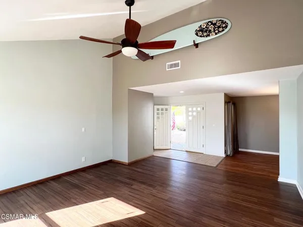 a view of an empty room with wooden floor and a ceiling fan