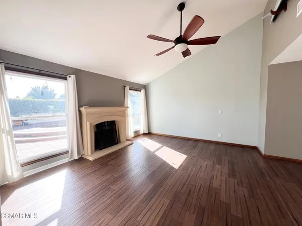 a view of empty room with wooden floor fireplace and a window