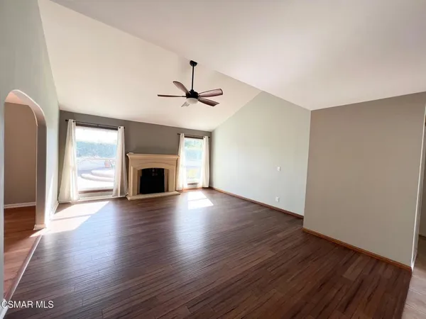 an empty room with wooden floor fireplace and windows