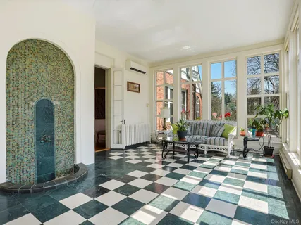 a living room with a black white checkered floor with a gaming machine and dining chairs