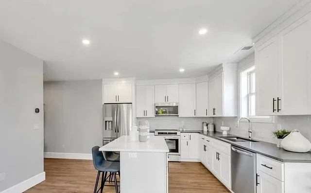 a kitchen with stainless steel appliances kitchen island granite countertop a sink refrigerator and cabinets