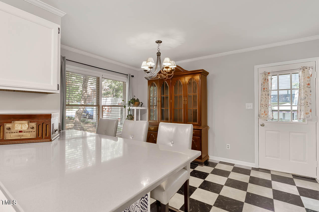 5525 Middleton Road Durham, NC 27713 - Photo 25 of 38 a dining room with wooden floor a chandelier a wooden table and chairs