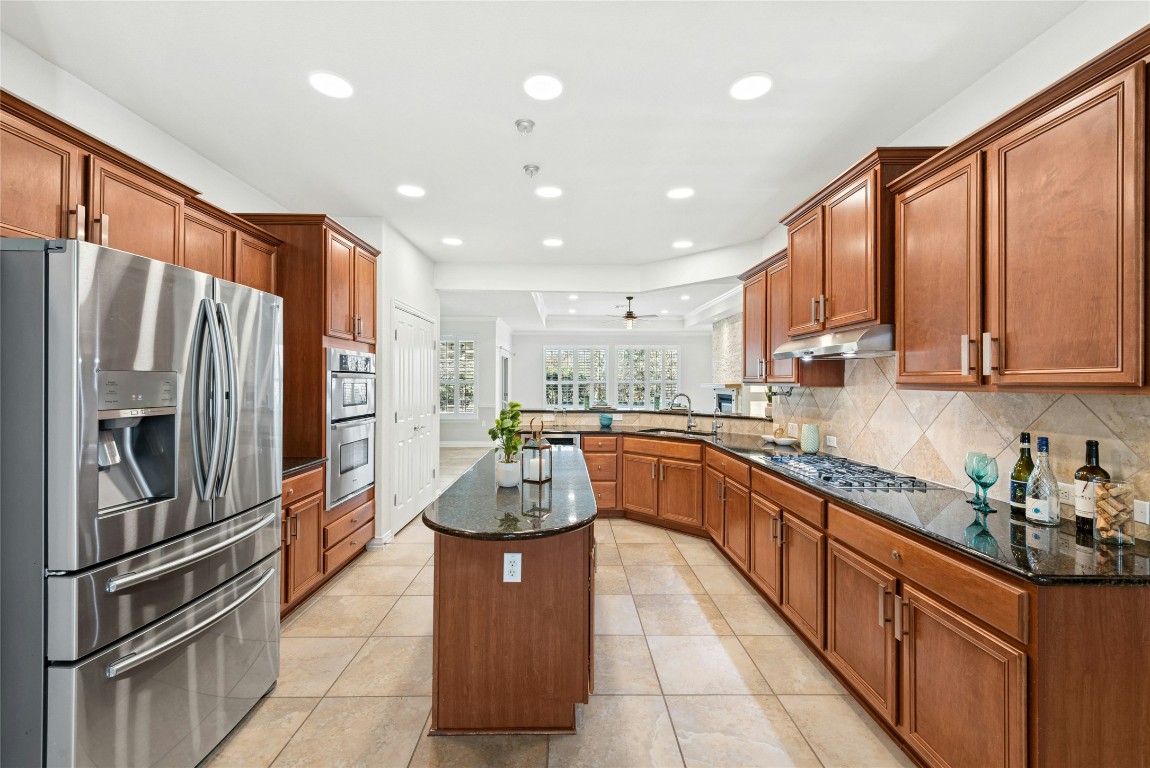 310 Pipe Creek Lane Georgetown, TX 78633 - Photo 12 of 35 a kitchen with stainless steel appliances granite countertop a refrigerator a sink a stove a oven with a dining table and chairs