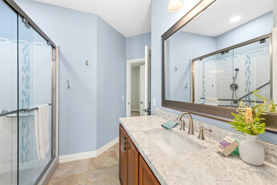 310 Pipe Creek Lane Georgetown, TX 78633 - Photo 24 of 35 a bathroom with a granite countertop sink a mirror and a shower