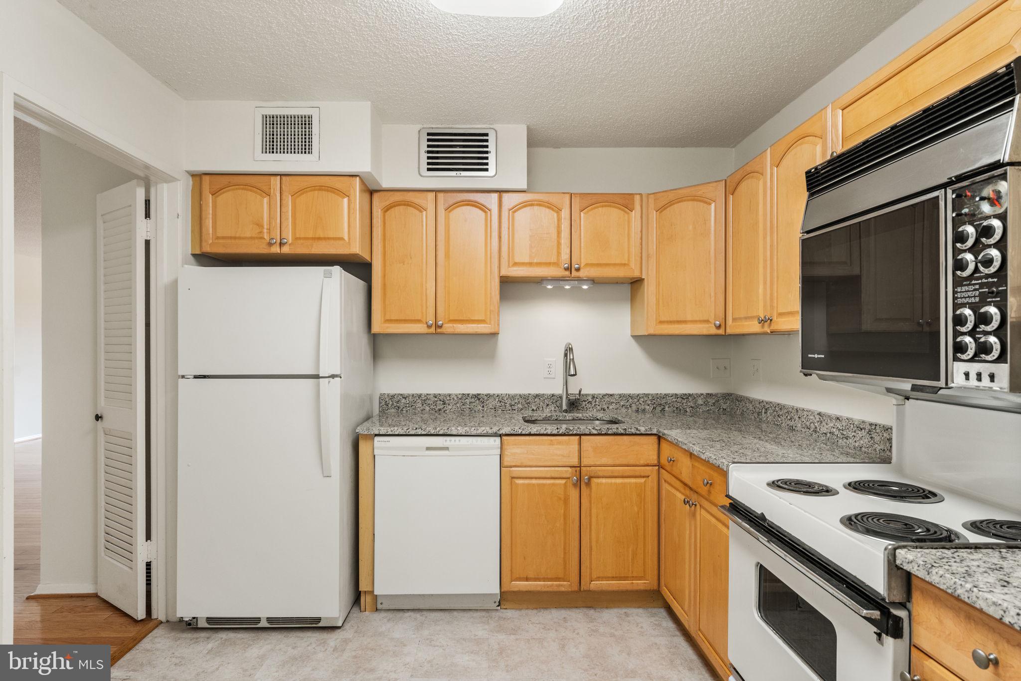 1800 Old Meadow Road, Unit 1218 McLean, VA 22102 - Photo 26 of 55 a kitchen with stainless steel appliances granite countertop a refrigerator a stove a sink and a microwave