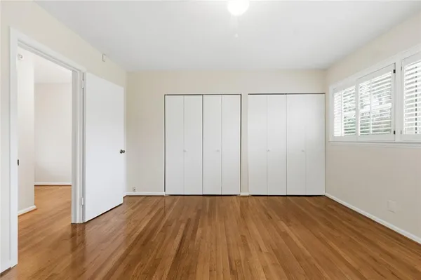 an empty room with wooden floor & windows
