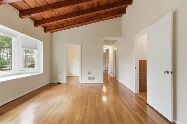 a view of an empty room with wooden floor and a window
