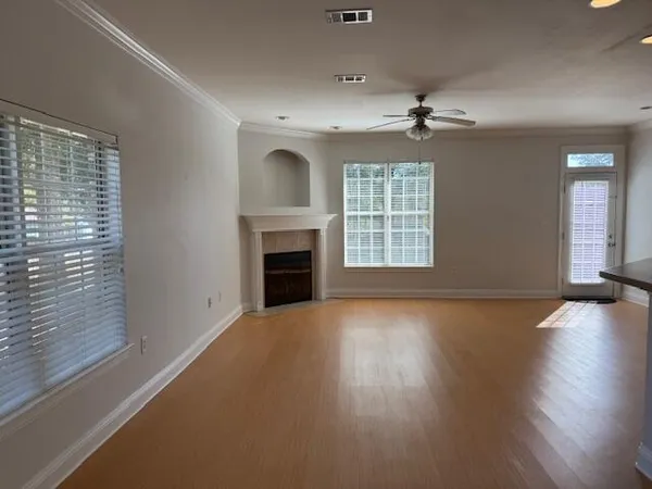 an empty room with windows fireplace and wooden floor