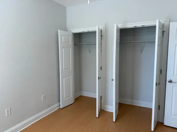 a view of an empty room with closet and wooden floor