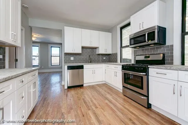 a kitchen with stainless steel appliances kitchen island granite countertop a stove a sink and white cabinets