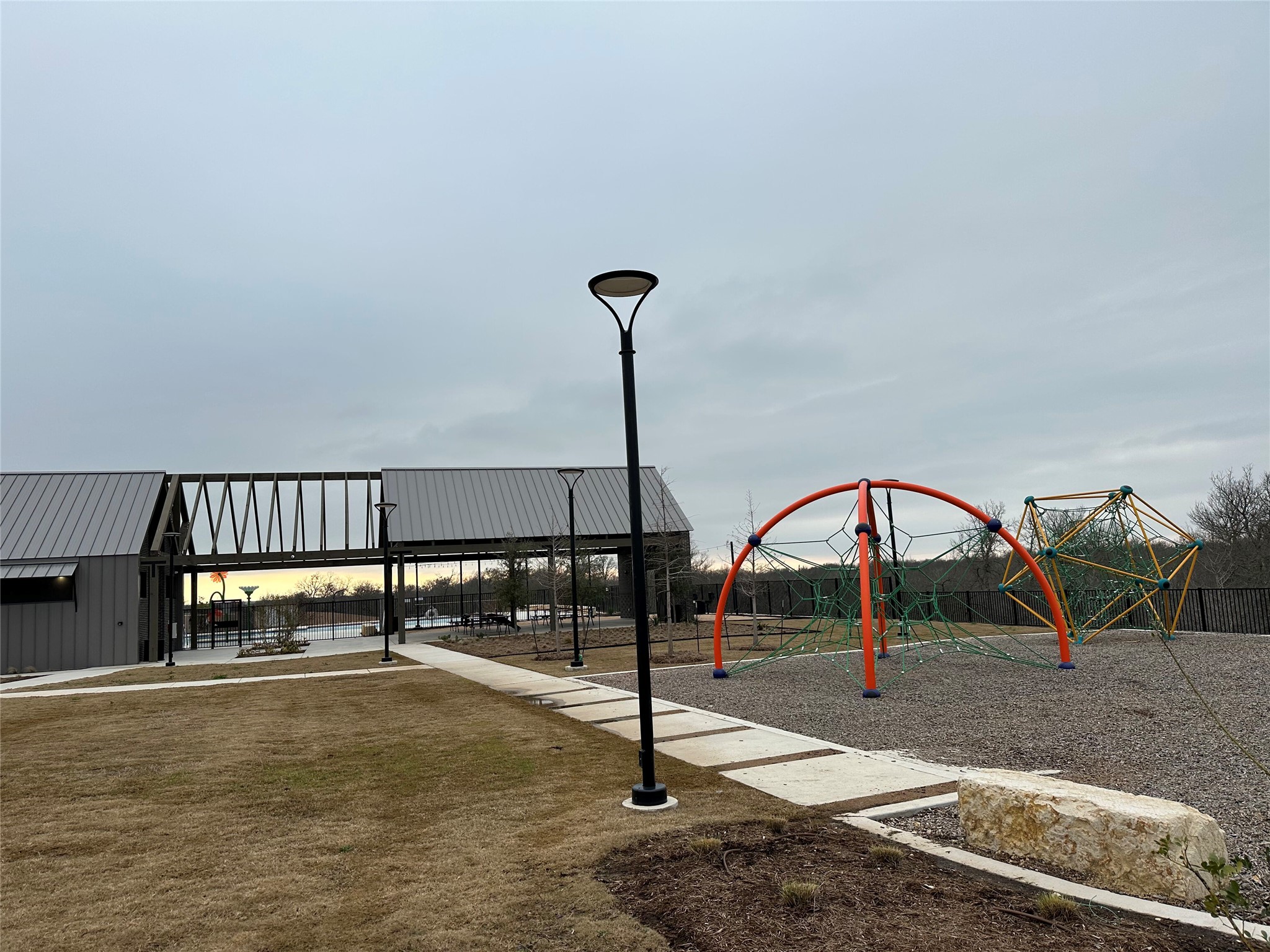 13501 Mussel Run Elgin, TX 78621 - Photo 25 of 28 Community recreational area featuring a modern playground with climbing structures, a walking path with integrated lighting, and a contemporary covered structure with a metal roof