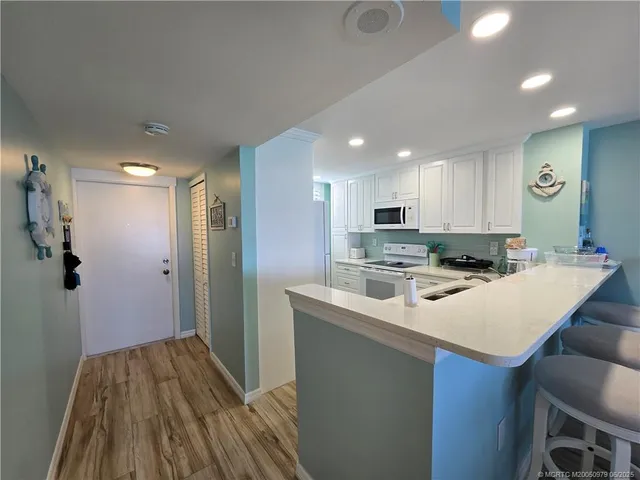 a kitchen with a sink a refrigerator and wooden floor