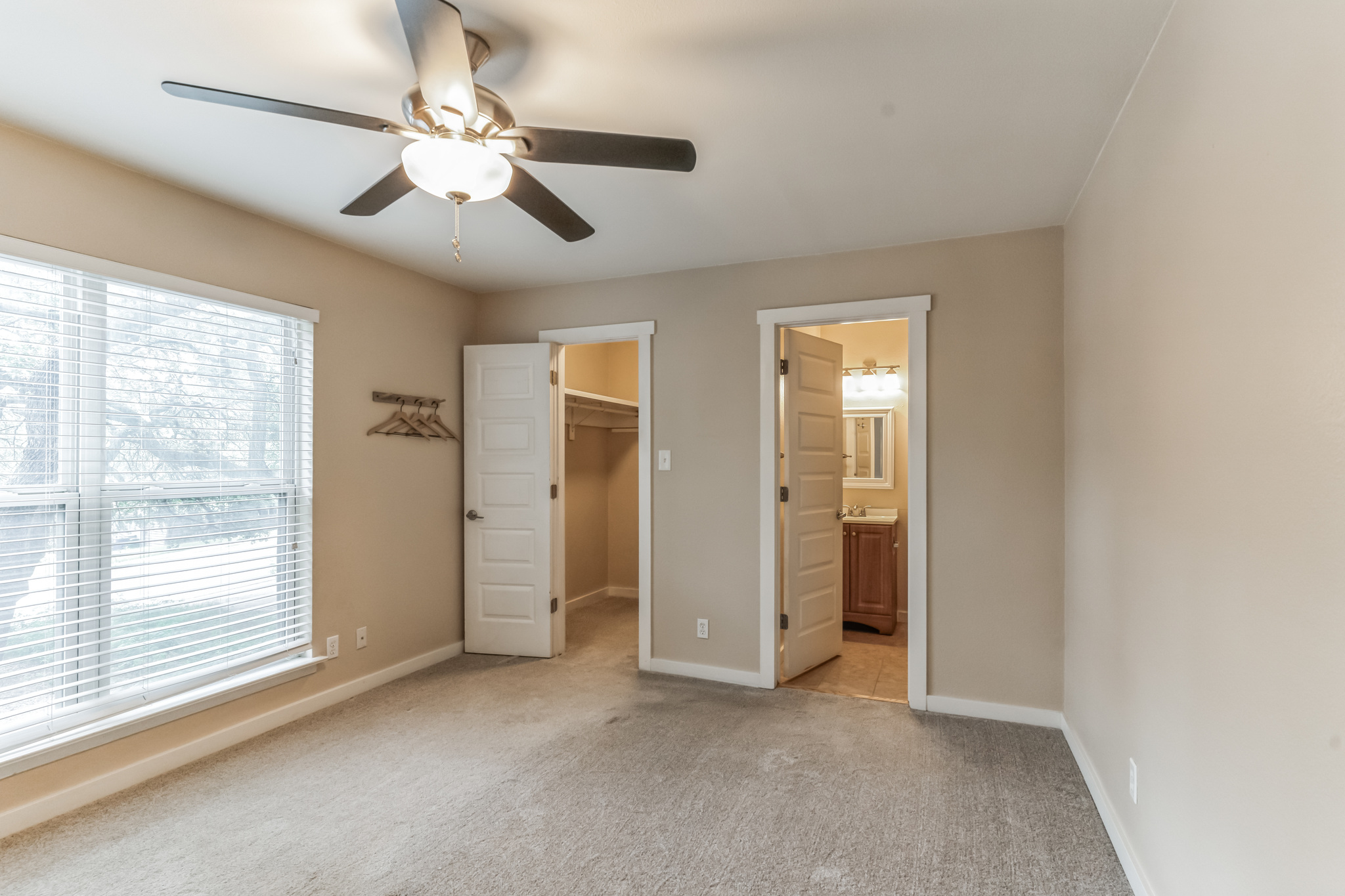3214 Clawson Road, Unit A Austin, TX 78704 - Photo 9 of 26 A well-lit bedroom features plush carpeting, a wide window with blinds, and convenient access to both a closet and an adjoining bathroom.