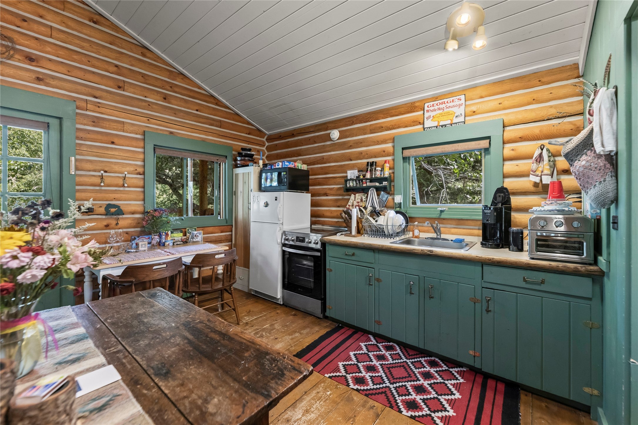 380 West Boulder Road McLeod, MT 59052 - Photo 47 of 77 Cabin kitchen with stainless steel electric range oven, vaulted ceiling, wood-type flooring, freestanding refrigerator, and green cabinetry