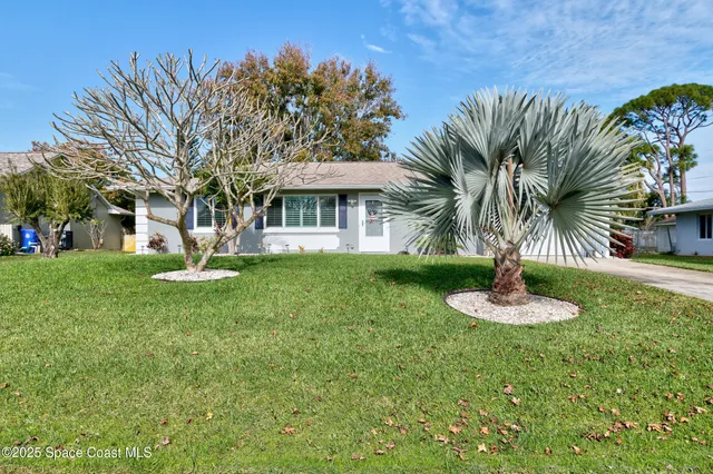 a front view of a house with garden and trees