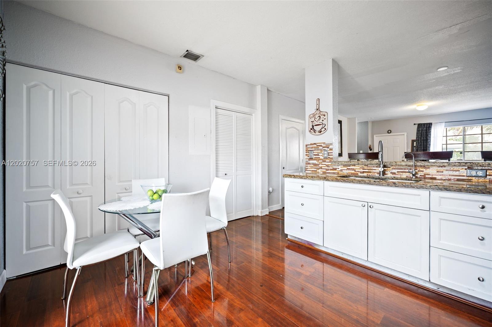 255 East 3rd Street, Unit 1 Hialeah, FL 33010 - Photo 6 of 38 a large white kitchen with granite countertop a stove a sink white cabinets and wooden floor